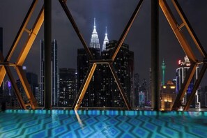Een nachtzicht van een stadsgezicht, met een opvallend gebouw met twee verlichte torens, gefotografeerd door een geometrische constructie met een patroon in de vloer.