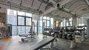 Uma academia com equipamentos de musculação, bancos e halteres.