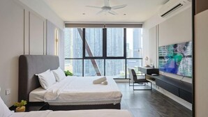 Quarto de hotel moderno com duas camas, televisão, escrivaninha e uma grande janela com vista para a cidade.