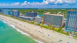 Een strandhotel met meerdere hoge gebouwen, een zandstrand en een heldere lucht.
