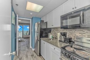 A modern kitchen with a refrigerator, microwave, stove, and coffee maker. - 1416 Sandcastle South-Surfs Up (Myrtle Beach)