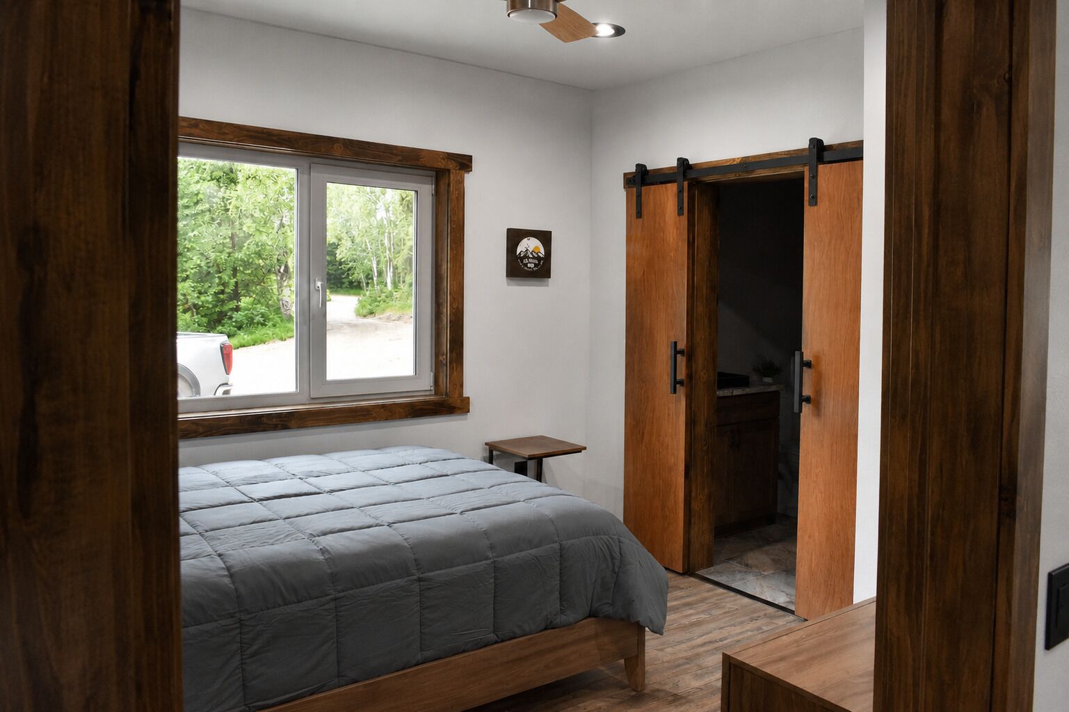 Quarto com cama, uma mesinha de cabeceira, janela e porta de correr para um armário.