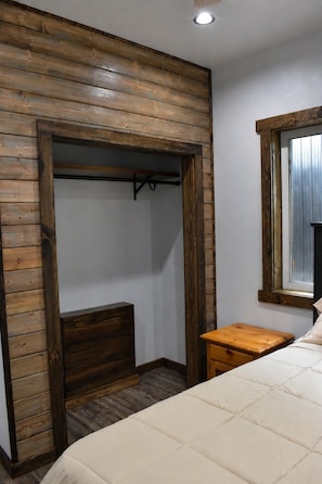 Un dormitorio con un armario de madera, una mesita de noche y una ventana.