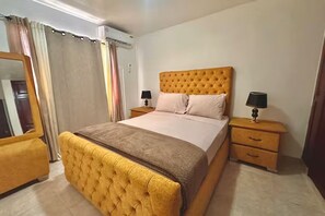 Un dormitorio con una cama grande, dos mesitas de noche, un espejo y un armario.