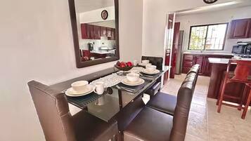 Un área de comedor con una mesa de vidrio, sillas de cuero marrón y un espejo grande sobre ella.