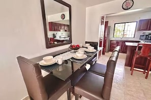 Un área de comedor con una mesa de vidrio, sillas de cuero marrón y un espejo grande sobre ella.