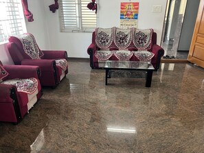 A seating area with two armchairs and a sofa, all covered with patterned cushions.