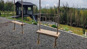 Un parque infantil con columpios, un tobogán y un pequeño refugio.