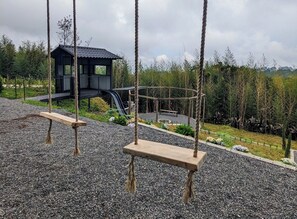A playground with swings, a slide, and a small shelter.