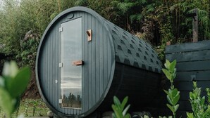 A cylindrical building with a door, surrounded by greenery.