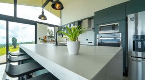 Una cocina moderna con una isla grande, electrodomésticos de acero inoxidable y vistas al exterior.