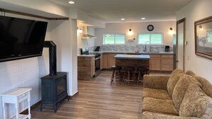Una cocina moderna con televisor integrado, armarios de madera, una isla central y una zona de estar acogedora.
