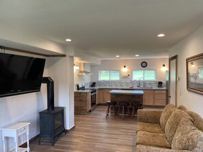 Una cocina moderna con televisor integrado, armarios de madera, una isla central y una zona de estar acogedora.