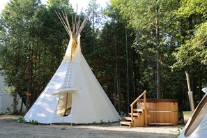 A white teepee with a ladder, wooden steps, and a hot tub in a forest setting. - Sitting Bull, Tipi for group of 6 (Markdale)
