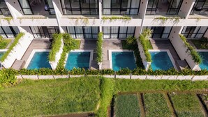 A modern building with multiple swimming pools, a rooftop garden, and a view of the surrounding landscape. - Serenity Ubud by Betterplace (Ubud)