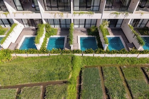 A modern building with multiple swimming pools, a rooftop garden, and a view of the surrounding landscape. - Serenity Ubud by Betterplace (Ubud)