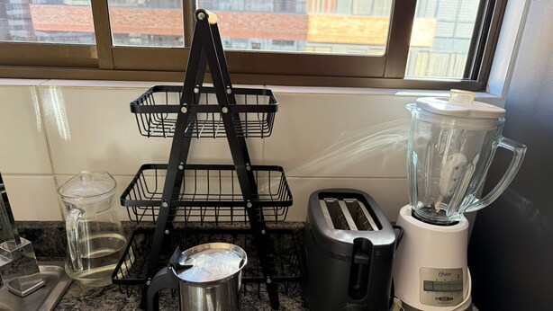 Ett kök med en kaffebryggare, brödrost, mixer och en kastrull i metall på bänkskivan.