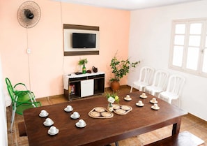 A room with a wooden table set for tea, a TV mounted on the wall, a cabinet, and a potted plant. - Barreirinhas House, near...  Lençois Maranhenses, come with a group of up to 14 people. (Barreirinhas)
