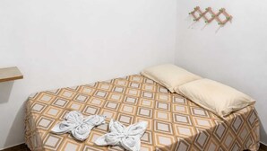 Uma cama de solteiro com colcha estampada, duas almofadas e duas toalhas sobre a cama.