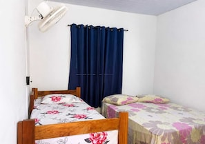 A room with two wooden beds, a wall-mounted fan, and a window with dark curtains. - Barreirinhas House, near...  Lençois Maranhenses, come with a group of up to 14 people. (Barreirinhas)
