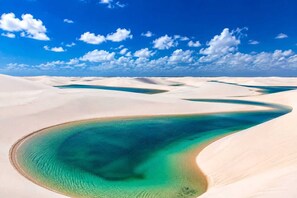 A desert landscape with sand dunes and a turquoise body of water. - Barreirinhas House, near...  Lençois Maranhenses, come with a group of up to 14 people. (Barreirinhas)