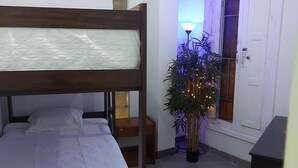 Habitación con literas, una mesita de noche, una lámpara y una planta en maceta.