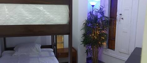 A bunk bed room with a bedside table, a lamp, and a potted plant.