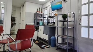Una cocina moderna con zona de comedor, un televisor montado en la pared y un cubo de basura azul.