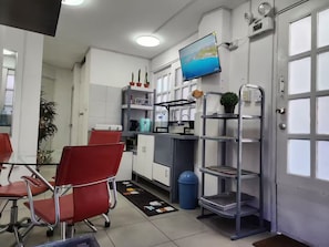 A modern kitchen with a dining area, a TV mounted on the wall, and a blue trash bin. - 2-Bedroom Apartment in Historic Downtown Lima (Lima)