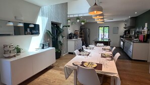 A modern kitchen with a dining area, wooden flooring, and pendant lighting.