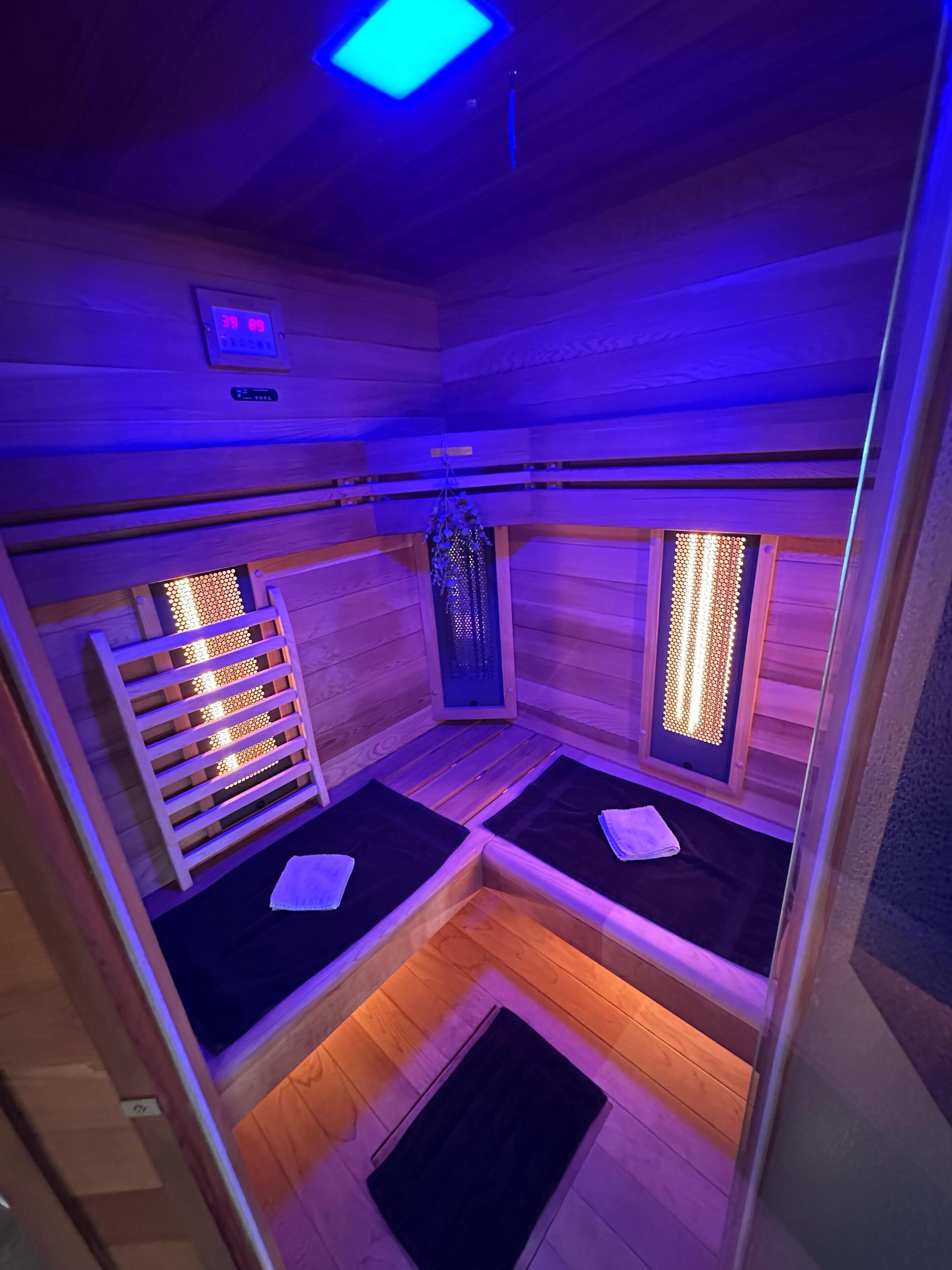 Een sauna met houten wanden, twee banken, een houten rek en een raam met verlichting.