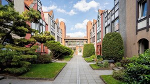 A pathway leading to a building with a central entrance, flanked by greenery and traditional architecture. - Stągiewna Old Town Apartment (Gdańsk)