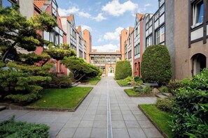A pathway leading to a building with a central entrance, flanked by greenery and traditional architecture. - Stągiewna Old Town Apartment (Gdańsk)
