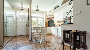 A spacious kitchen with white cabinets, a dining area with a white table and chairs, and a decorative wooden side table. - Stągiewna Old Town Apartment (Gdańsk)