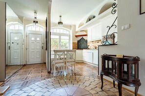 A spacious kitchen with white cabinets, a dining area with a white table and chairs, and a decorative wooden side table. - Stągiewna Old Town Apartment (Gdańsk)