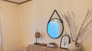 A wooden cabinet with a mirror, a vase with branches, and a small lamp.