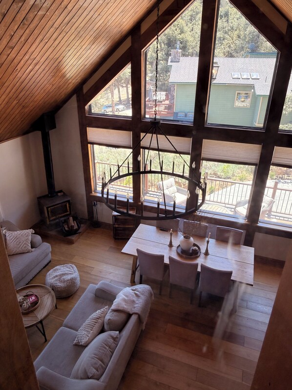 Un loft acogedor con techo de madera, un comedor con candelabro, un sofá y una chimenea.