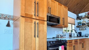 A modern kitchen with wooden cabinets, a stainless steel oven, and a microwave.