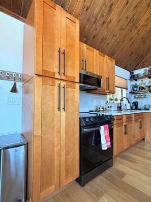 Una cocina moderna con armarios de madera, horno de acero inoxidable y microondas.