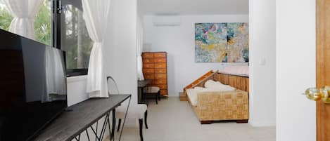 A bedroom with a bed, a TV, a desk, and a dresser.