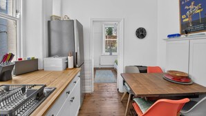 A compact kitchen with a refrigerator, a sink, and a dining area with chairs. - Stylish Two Bedroom Apartment (London)