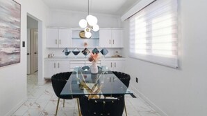 Een moderne keuken met witte kasten, een glazen eettafel en een decoratieve vaas.
