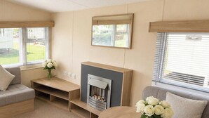 Un salon moderne avec une cheminée, des canapés, une table basse et une vue sur l’extérieur.
