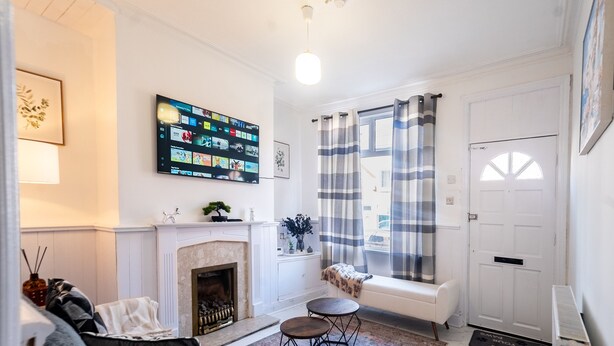 Ein Wohnzimmer mit Kamin, einem an der Wand montierten Fernseher, einer Bank und einer Tür mit Fenster.