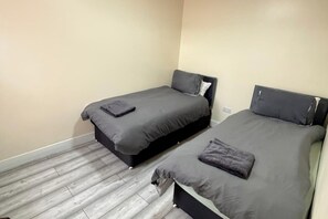 A room with two single beds, each with a pillow and a folded blanket. - 3 Bed House Long Stays Fast Wi-Fi & Parking (Bedford)