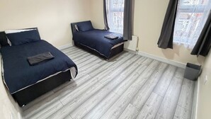 Een slaapkamer met twee bedden, een radiator en een raam met gordijnen.