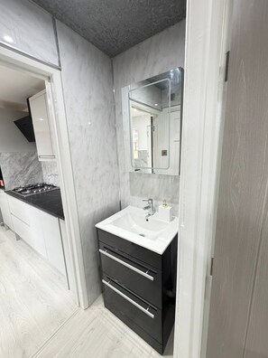 Ein modernes Badezimmer mit einem weißen Waschbecken, einem Spiegel und einem schwarzen Schrank.