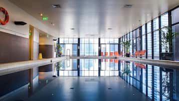 A spacious indoor area with a reflective floor, large windows, and exit signs.