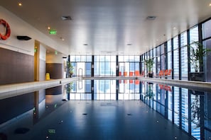 A spacious indoor area with a reflective floor, large windows, and exit signs. - Exclusive Stays - Gallery Penthouse (Southbank)