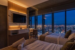 A modern hotel room with a large TV, two beds, a desk, and a city view. - The R Line I UT Skyline Studio I Pool (Ciudad de Mexico)
